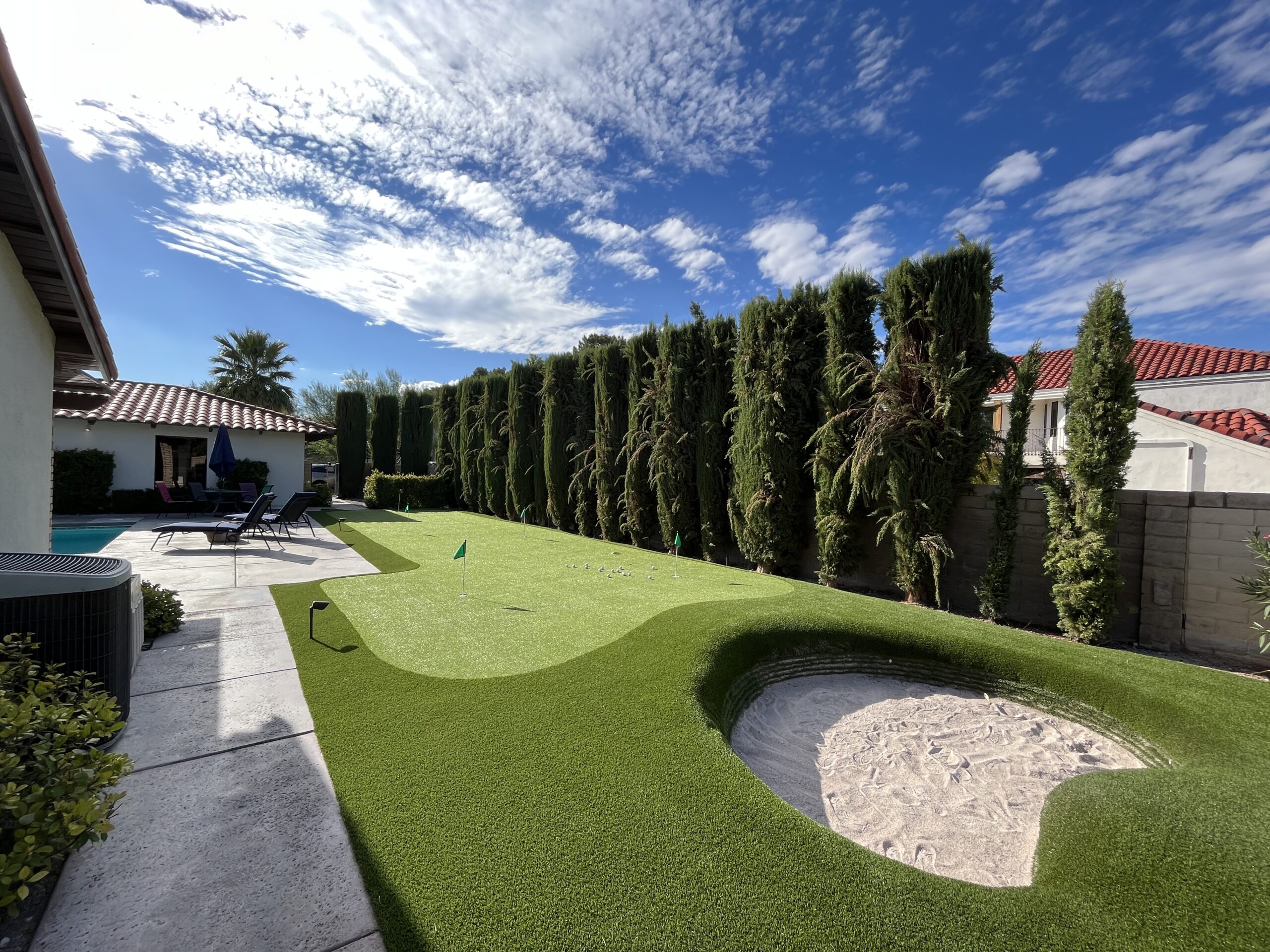 A backyard with a putting green and a small hole.