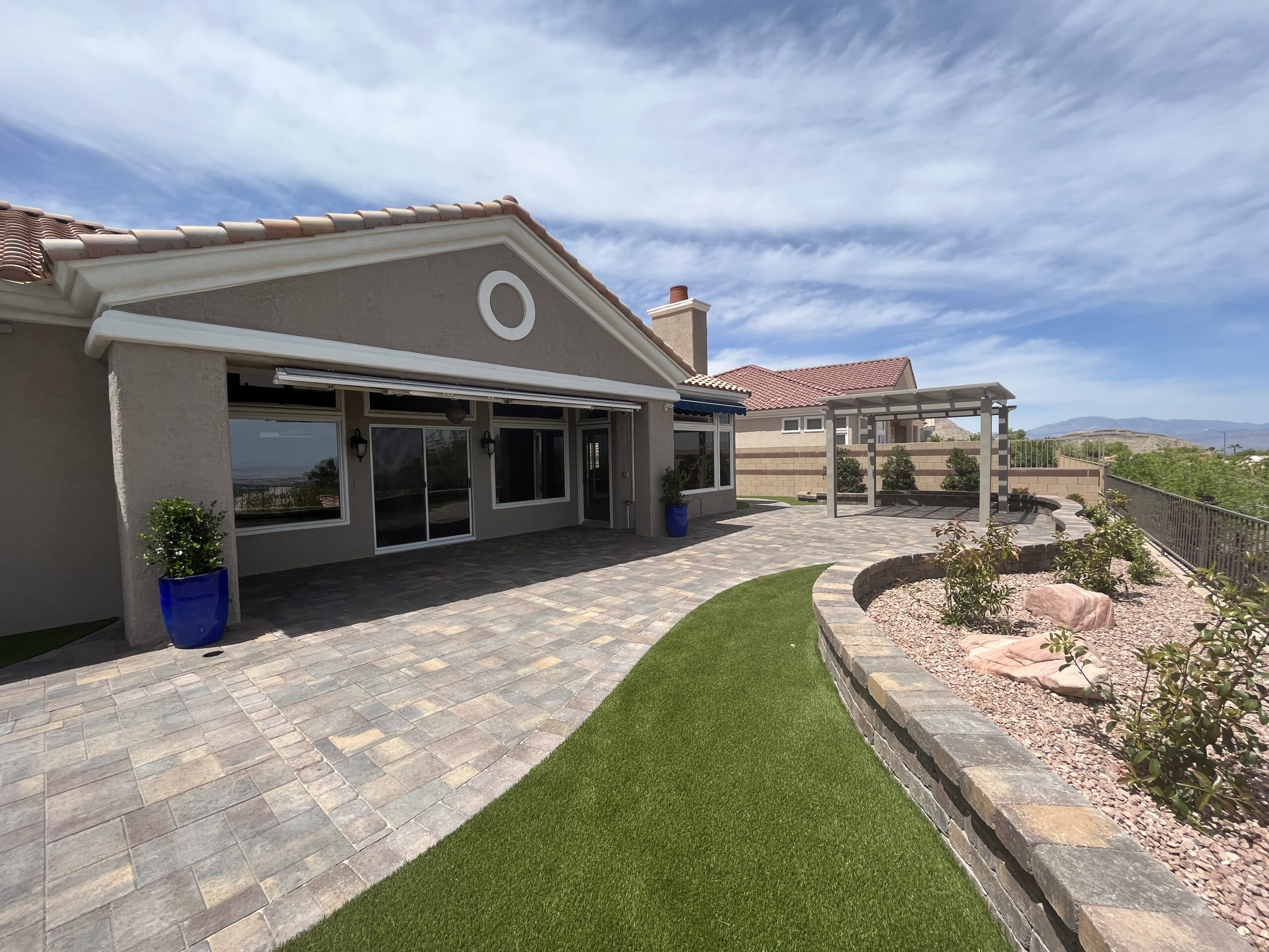 A patio with grass and a pergola in the middle of it.