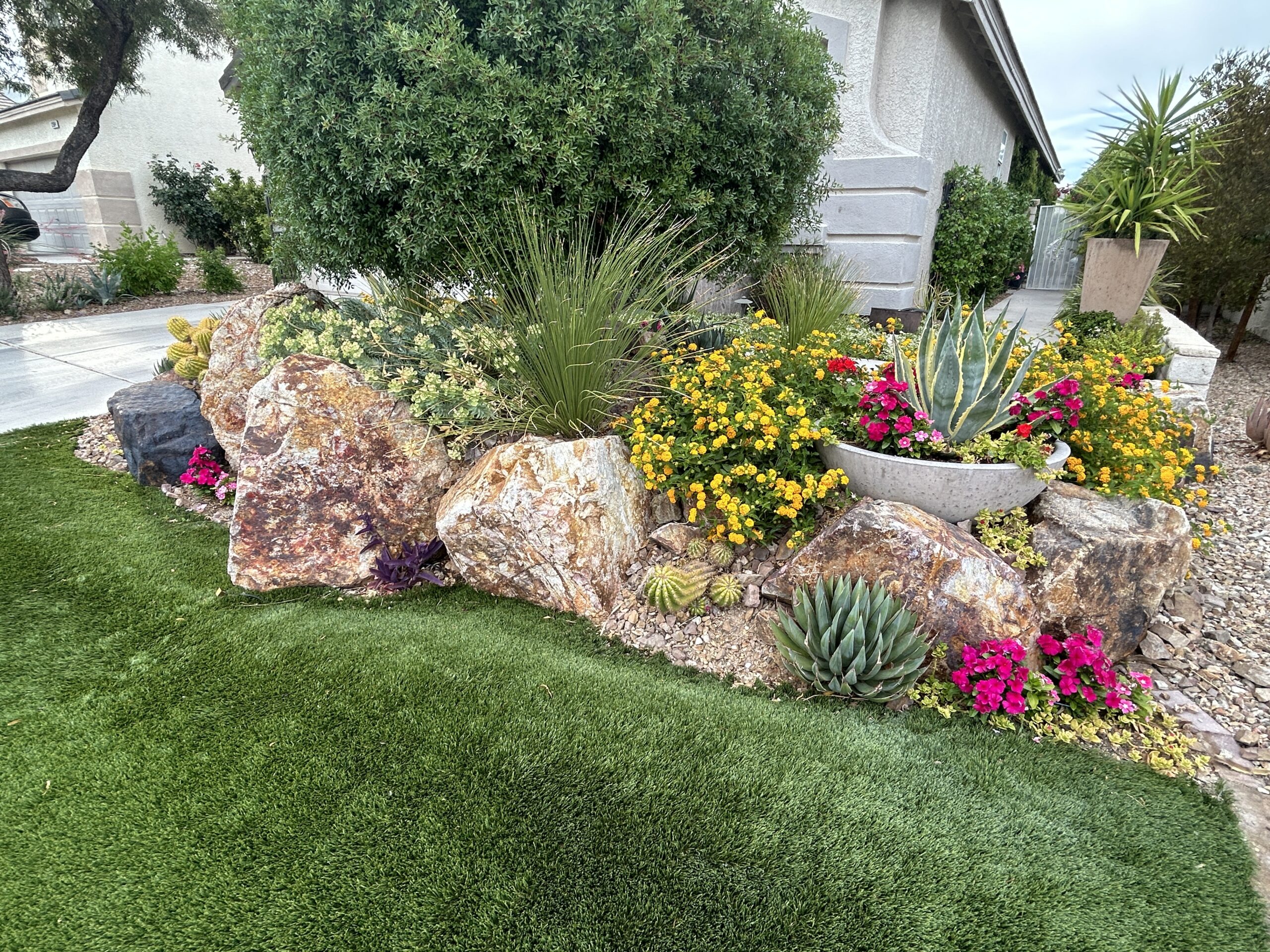 A garden with flowers and rocks in the grass.