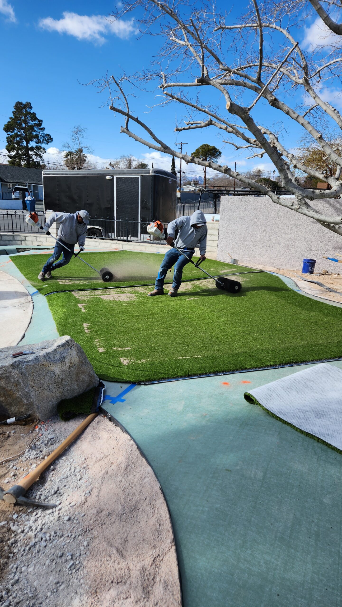 Two men are working on a fake grass field.