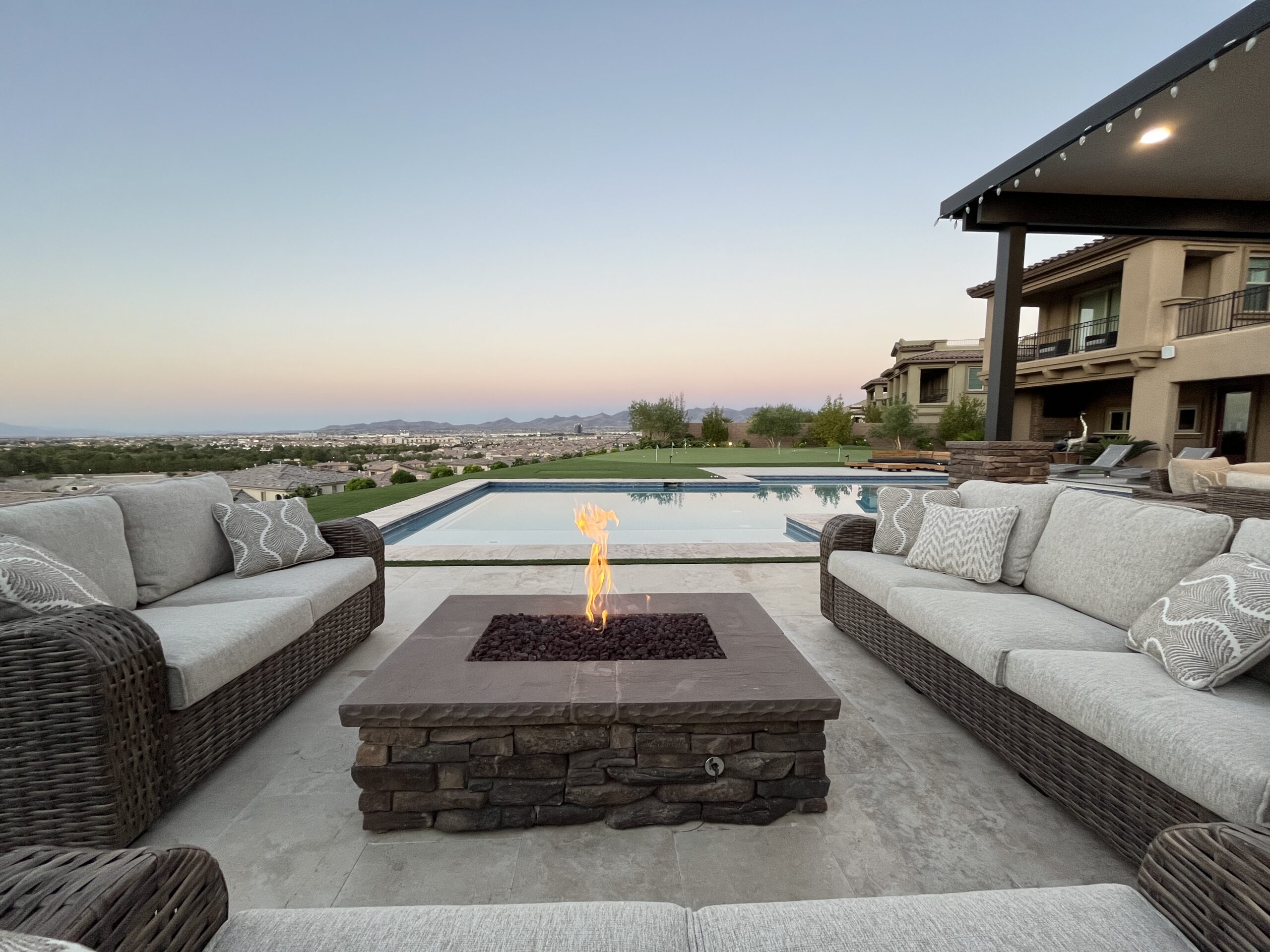 A fire pit sitting next to a pool in the middle of a patio.