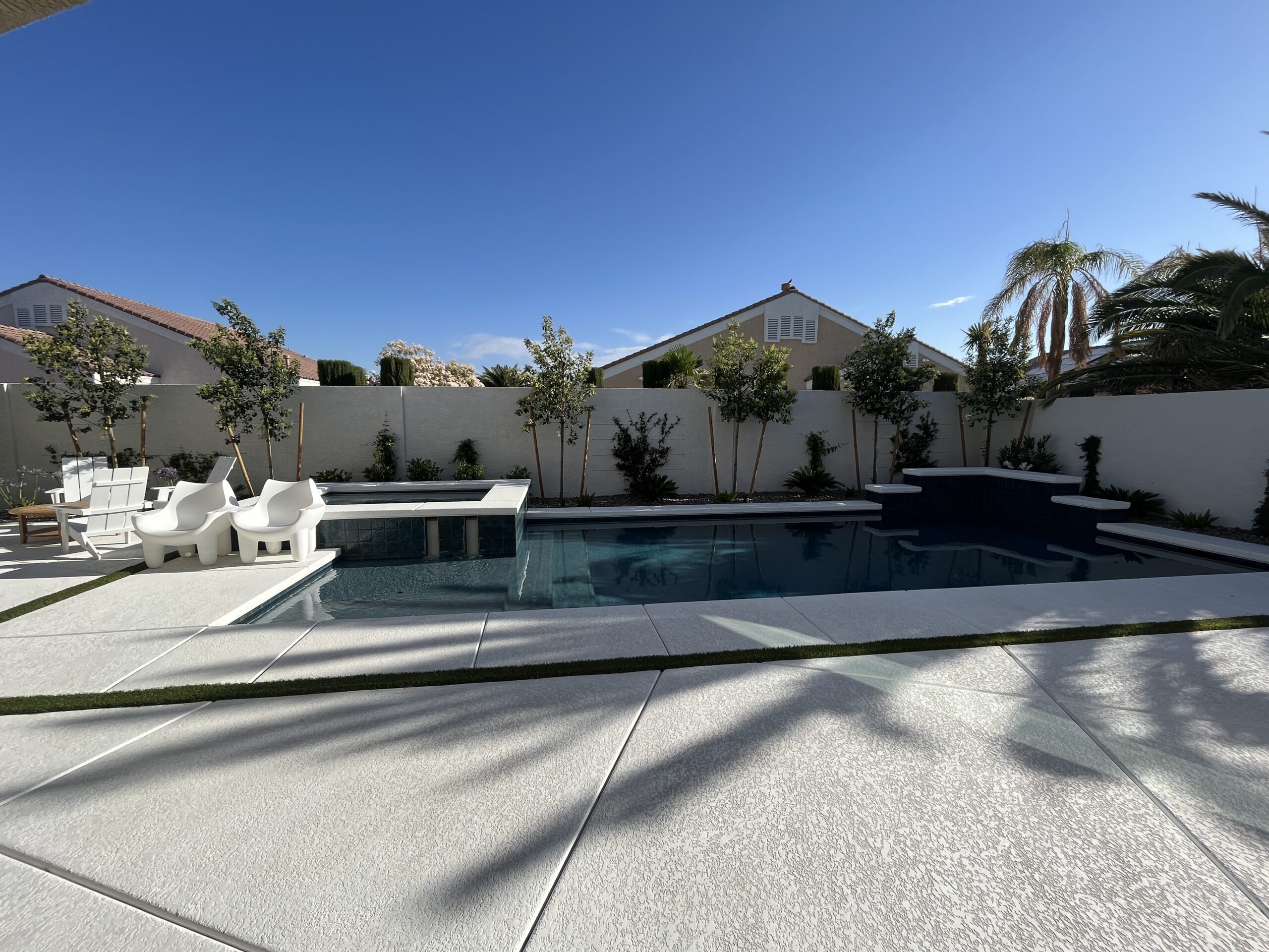 A pool with chairs and trees in the background