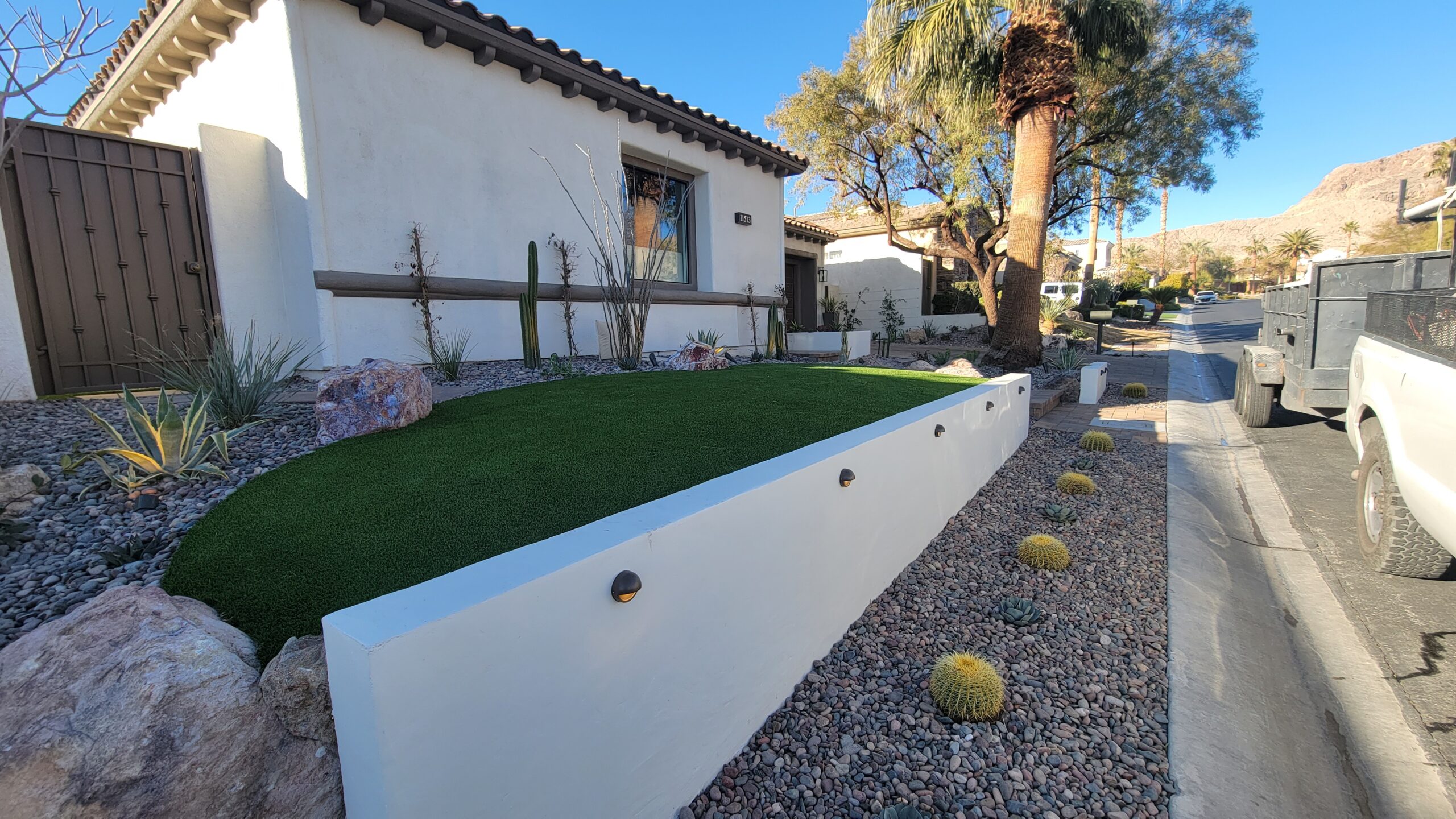 A white wall with holes in it next to a yard.