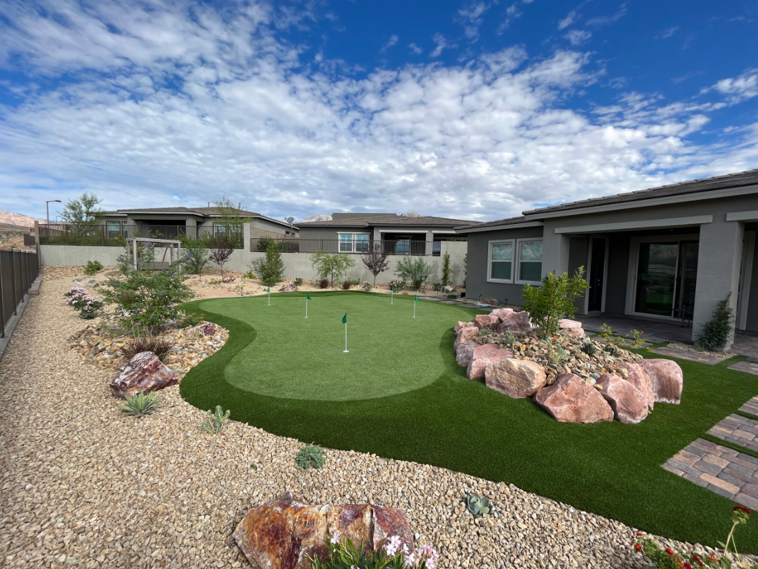 A backyard with a putting green and rocks.