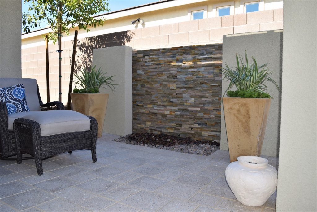 A patio with a stone wall and two large planters.